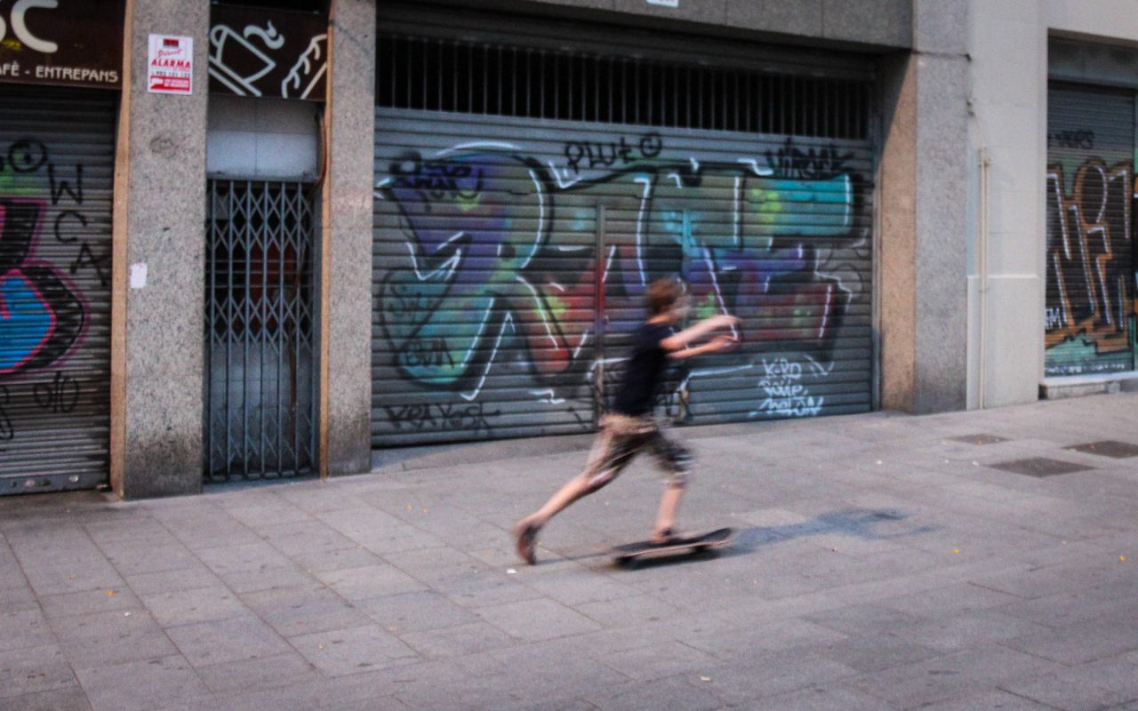 A skateboarder rides past a wall covered in colourful graffiti