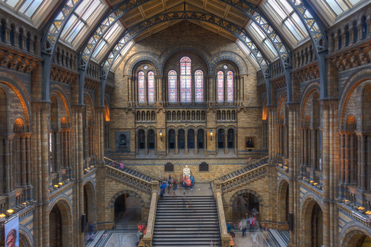 The vaulted stone interior of a grand museum hall with a central staircase