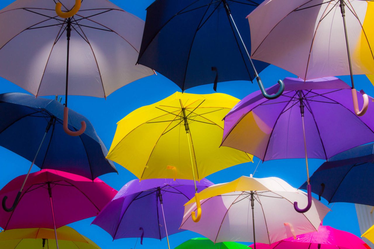 Brightly coloured umbrellas suspended overhead against the sky