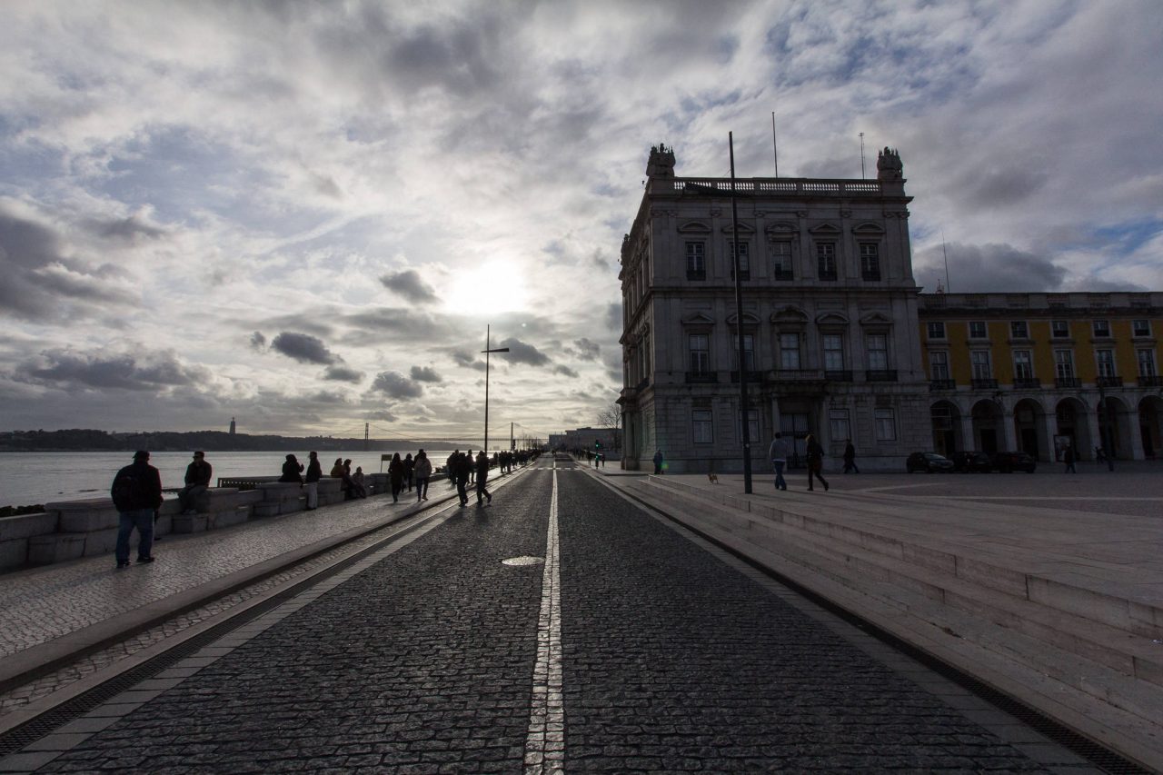 Tram tracks leading towards a riverside square at sunset
