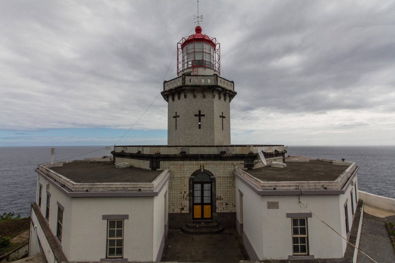 The front façade of a white and red lighthouse against a cloudy sky