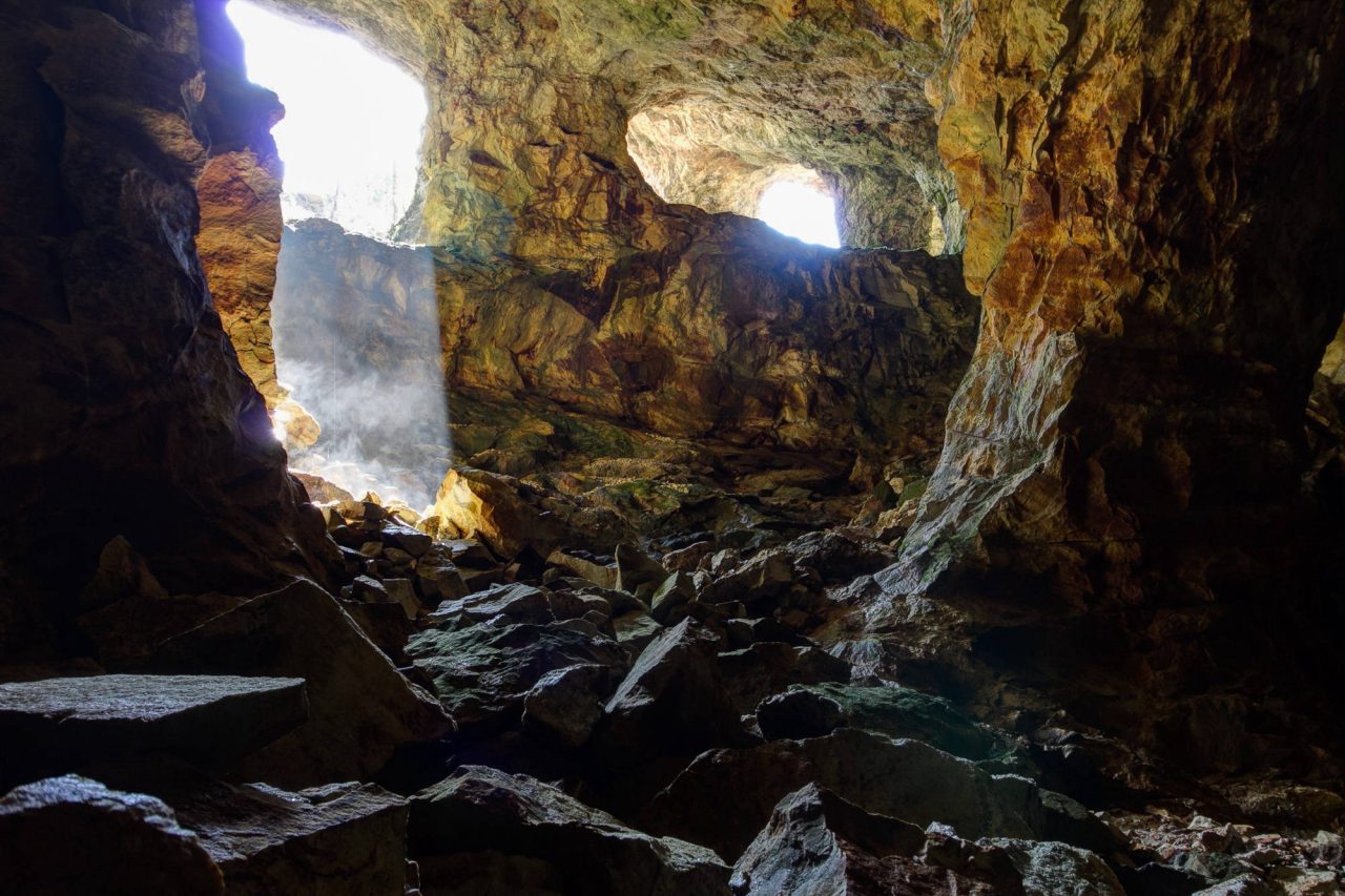 Daylight breaking through a hole in a cave roof onto wet rock