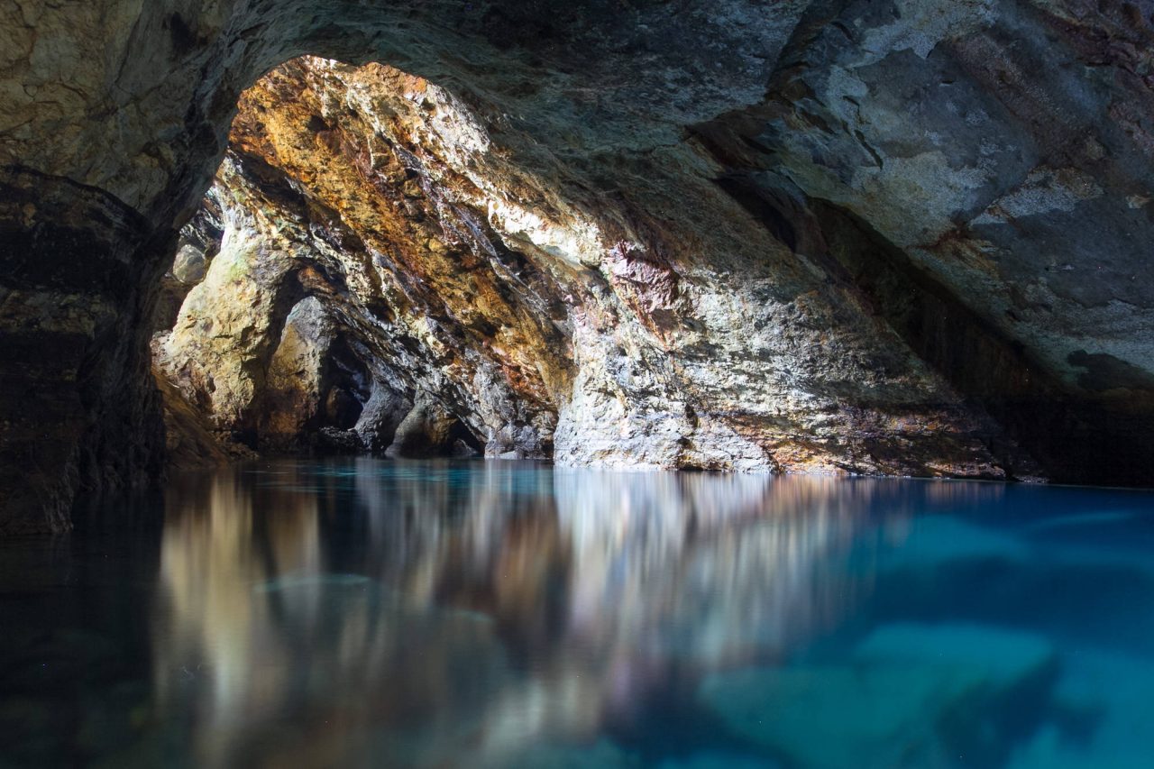 A cave arch reflected in a still turquoise underground lagoon