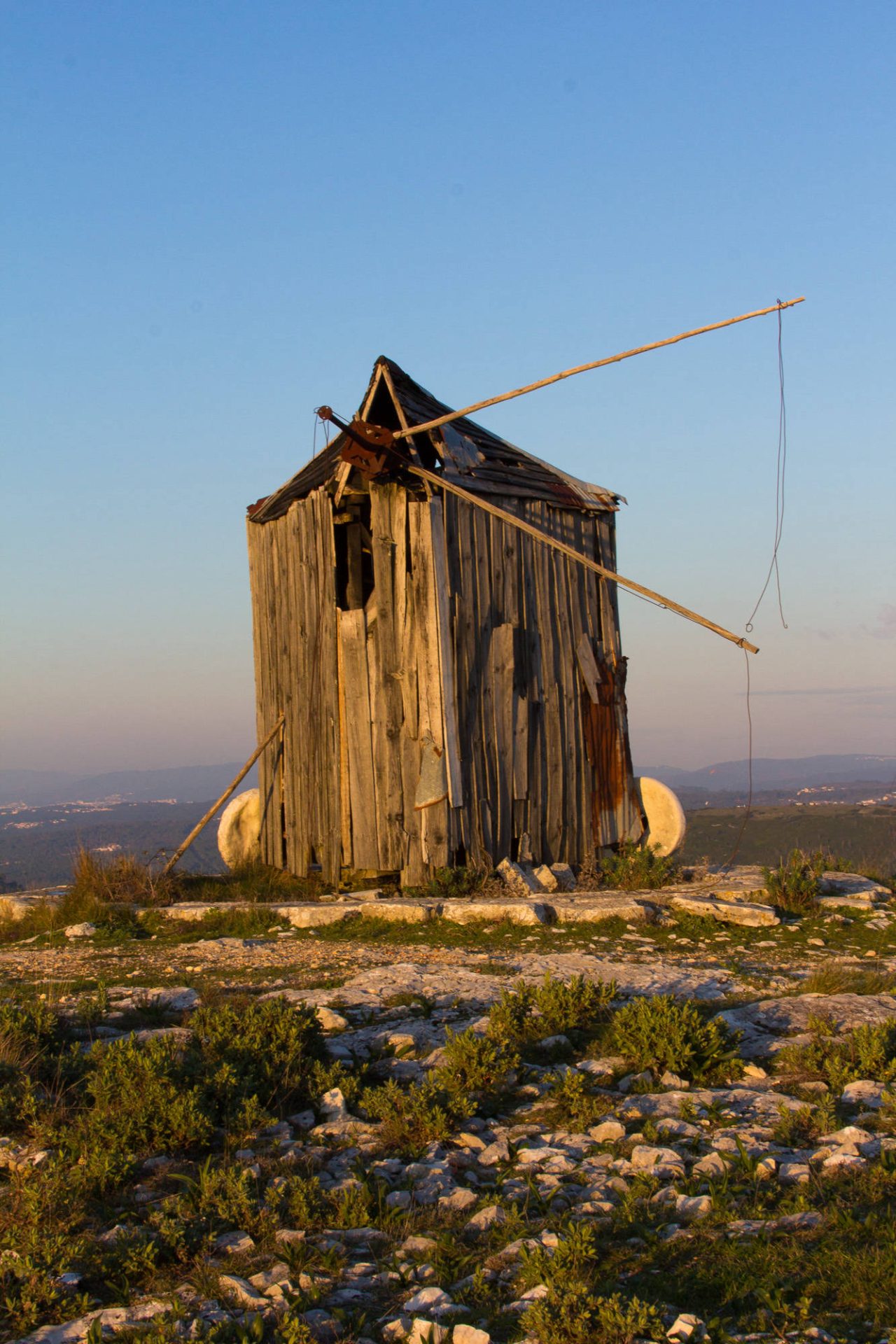 An old stone windmill on a hillside at golden hour