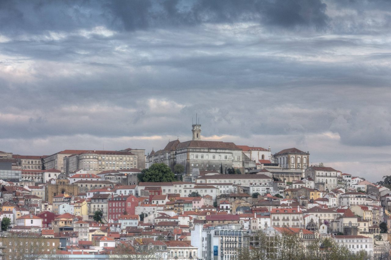 A hillside city of red rooftops rising to a tower on the skyline
